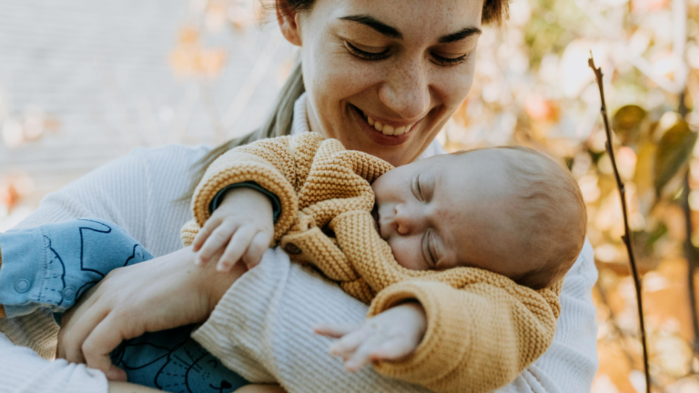 A mother carrying an infant and having a fall photoshoot with her