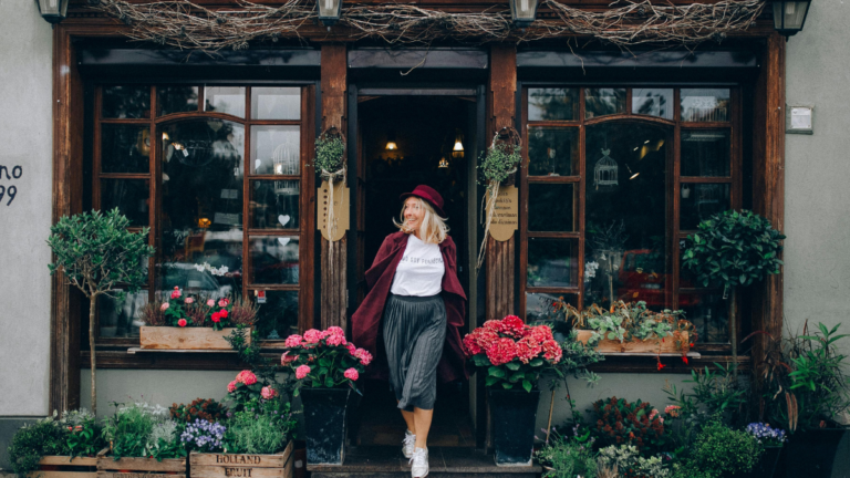 A woman coming out of a flower shop in fall season wearing a chic dress look